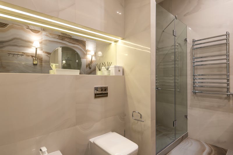 Rörmokare installerar nya kopparrör i ett badrum under renovering, väggen öppen med tätskikt synligt