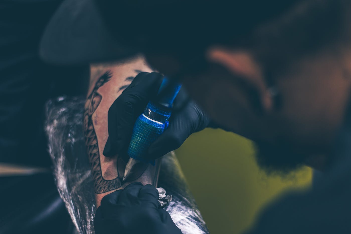 André Osman som tatuerar ett geometriskt mönster på en kunds underarm, fokuserad och med stadiga händer, studion i bakgrunden