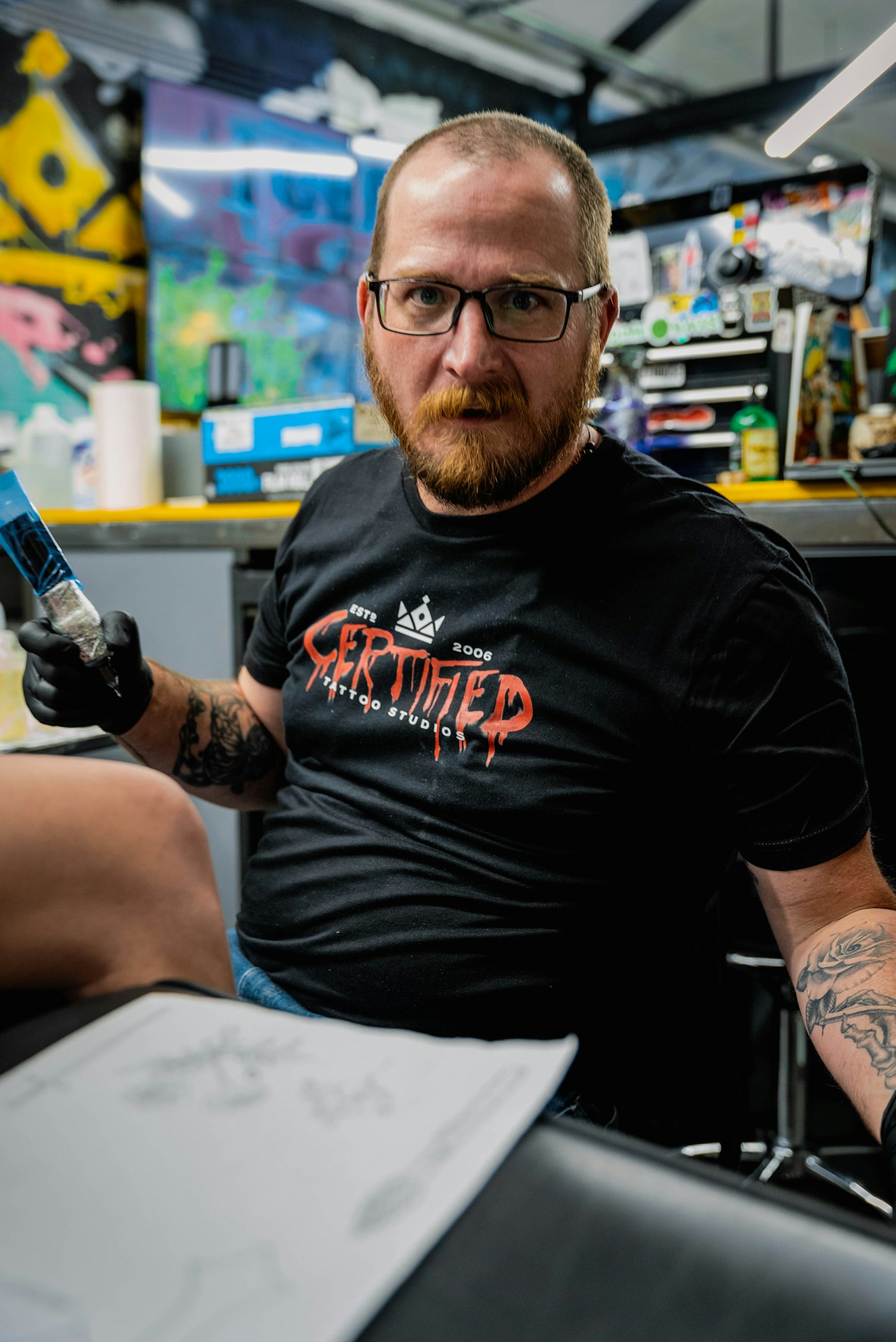 Joel Eriksson vid sin arbetsstation, koncentrerad över en skissbok med realistiska teckningar, omgiven av referensbilder på väggen