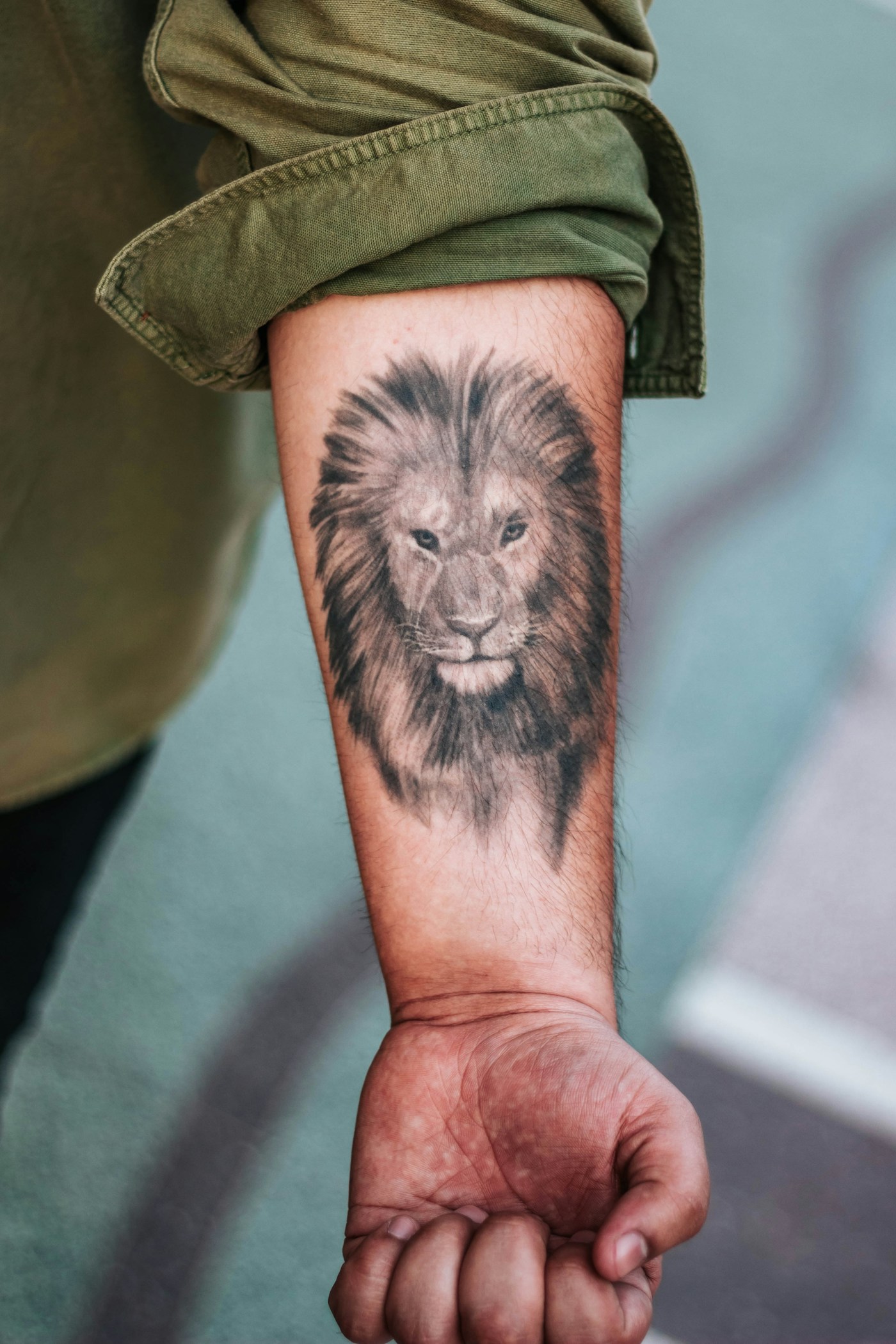 Detaljerad realistisk svartvit tatuering av ett lejonporträtt på en överarm, skarpa skuggor och ljus textur i manen